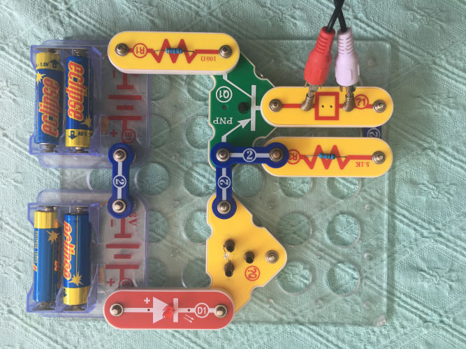 A PNP transistor is in series with a resistor, LED, and IR LED, and the Headphones are in series with a resistor connected to the emitter and base